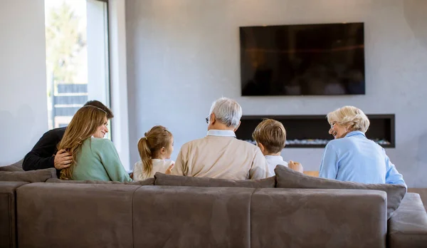 多代一家人一起坐在现代家里的沙发上看电视 — 图库照片