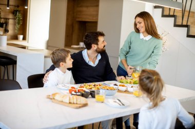 Genç anne modern mutfakta ailesine kahvaltı hazırlıyor.