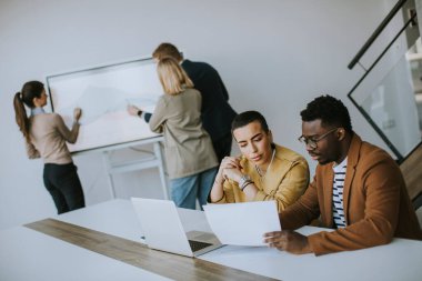 Çok ırklı genç iş adamlarından oluşan bir grup birlikte çalışıyor ve ofiste yeni bir proje hazırlıyorlar.