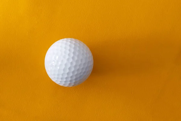 オレンジの背景にシングルゴルフボール — ストック写真