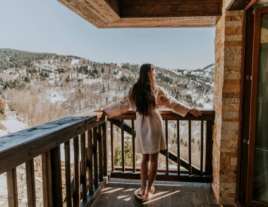 Bornozlu çekici genç bayanın kışın tadını çıkarırken büyük terasta.