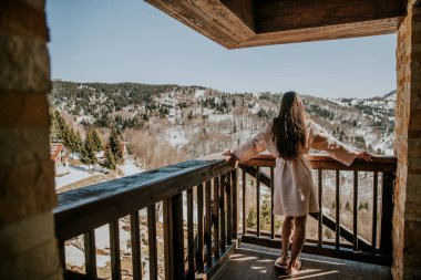 Bornozlu çekici genç bayanın kışın tadını çıkarırken büyük terasta.