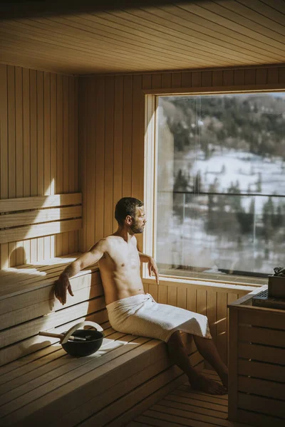 Красивый Молодой Человек Отдыхает Сауне Смотрит Зимний Лес Через Окно — стоковое фото