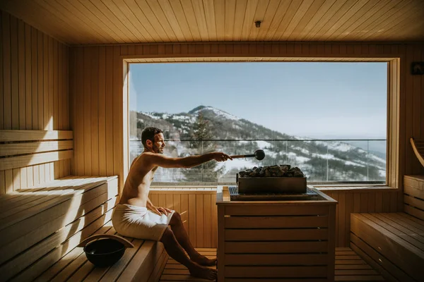 Bello Giovanotto Che Versa Acqua Sulla Pietra Calda Nella Sauna — Foto Stock