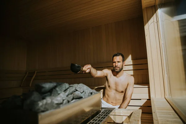 Schöner Junger Mann Gießt Der Sauna Wasser Auf Heißen Stein — Stockfoto
