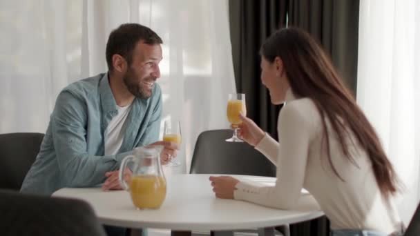 リビングルームで若いカップルとオレンジジュースを飲む — ストック動画