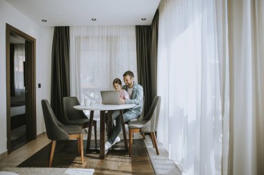 Baba ve kızı odada dizüstü bilgisayar kullanıyorlar.