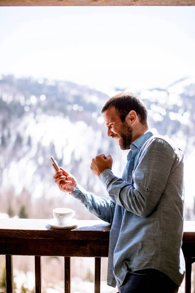 Bello Giovanotto Che Usa Cellulare Con Una Tazza Caldo Alla — Foto Stock