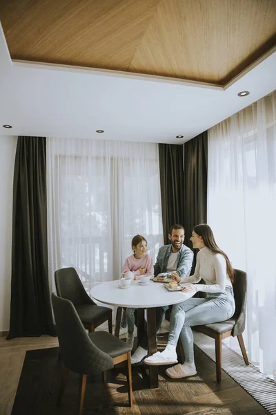 Genç ve mutlu bir aile kek yer ve odada çay içer.