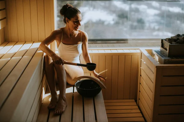 Çekici Genç Bir Kadın Saunadaki Sıcak Taşın Üzerine Döküyor — Stok fotoğraf
