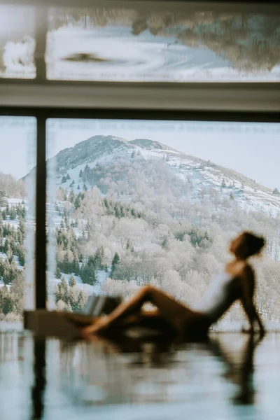 Güzel genç bir kadın kış vakti sonsuz yüzme havuzunda dinleniyor.