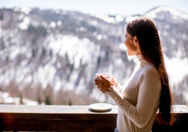 Kışın penceresinde bir fincan sıcak çayla güzel genç bir kadın.