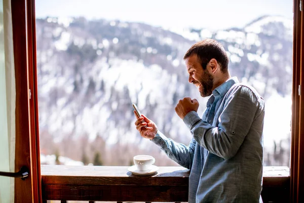 Bello Giovanotto Che Usa Cellulare Con Una Tazza Caldo Alla — Foto Stock