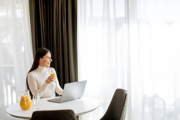 Jovem Mulher Usando Computador Portátil Beber Suco Laranja Saudável Sala — Fotografia de Stock