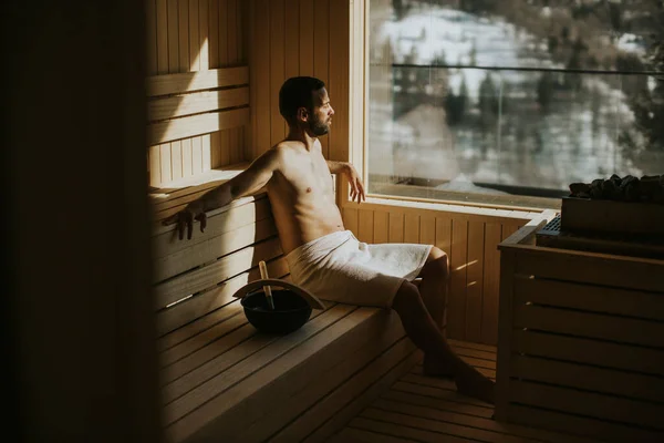 Joven Guapo Relajándose Sauna Viendo Bosque Invierno Través Ventana — Foto de Stock