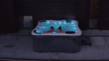 Romantik genç çift jakuzide ışıklarla dinleniyor.