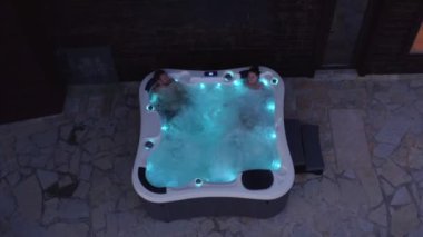 Romantik genç çift jakuzide ışıklarla dinleniyor.