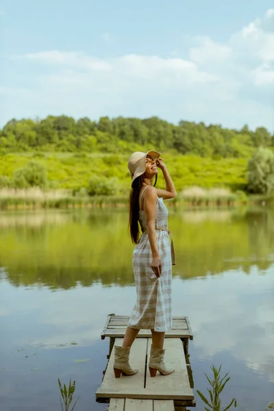 暑い夏の日 穏やかな湖の木製の桟橋に立つ若い女性 — ストック写真