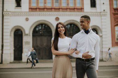 Sokakta yürüyen yakışıklı, etnik çeşitlilikte genç bir çift.