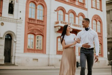 Sokakta yürüyen yakışıklı, etnik çeşitlilikte genç bir çift.