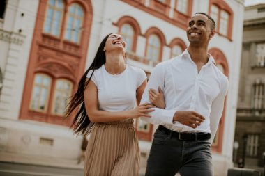 Sokakta yürüyen yakışıklı, etnik çeşitlilikte genç bir çift.
