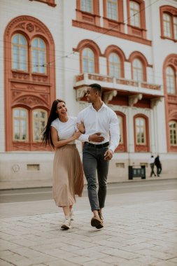Sokakta yürüyen yakışıklı, etnik çeşitlilikte genç bir çift.