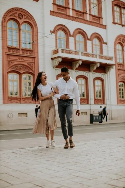 Sokakta yürüyen yakışıklı, etnik çeşitlilikte genç bir çift.