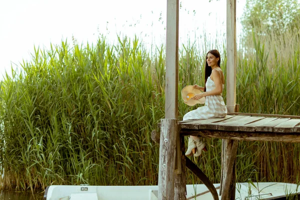暑い夏の日に穏やかな湖の木製の桟橋でリラックスした若い女性 — ストック写真