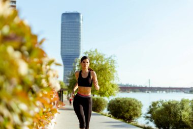 Güzel genç bayan nehir kenarında koşuya çıkıyor.