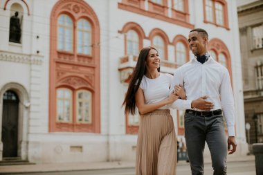 Sokakta yürüyen yakışıklı, etnik çeşitlilikte genç bir çift.