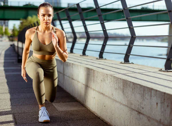 Spor giyimli güzel bir kadın nehir kenarında esniyor.