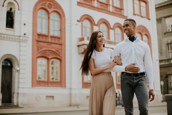 Sokakta yürüyen yakışıklı, etnik çeşitlilikte genç bir çift.