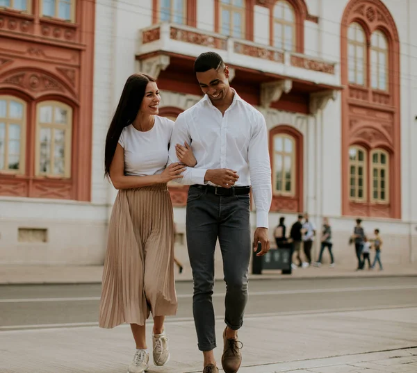 Sokakta yürüyen yakışıklı, etnik çeşitlilikte genç bir çift.