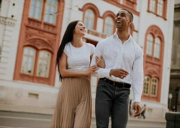 Sokakta yürüyen yakışıklı, etnik çeşitlilikte genç bir çift.