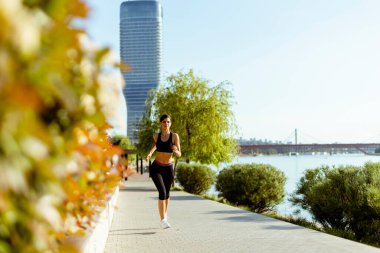 Güzel genç bayan nehir kenarında koşuya çıkıyor.