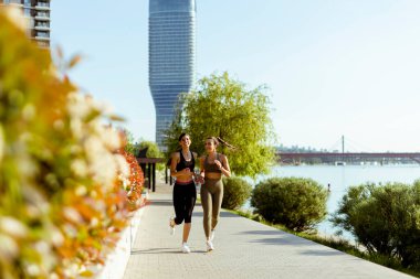 Güzel genç bayan nehir kenarında koşuya çıkıyor.