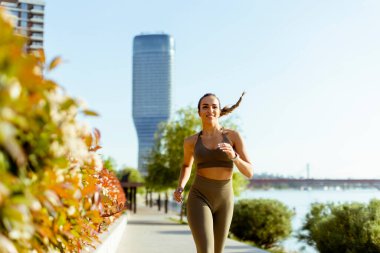Güzel genç bayan nehir kenarında koşuya çıkıyor.