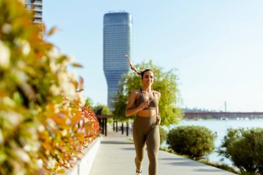 Güzel genç bayan nehir kenarında koşuya çıkıyor.