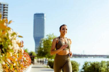 Güzel genç bayan nehir kenarında koşuya çıkıyor.