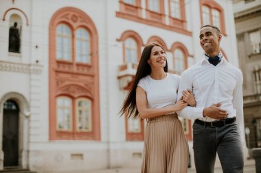 Sokakta yürüyen yakışıklı, etnik çeşitlilikte genç bir çift.