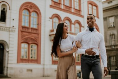 Sokakta yürüyen yakışıklı, etnik çeşitlilikte genç bir çift.