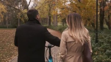 Sonbahar parkında bisiklet süren genç bir çift.