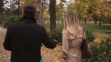 Genç çift sonbahar parkında yürüyor.
