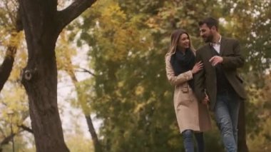 Genç çift sonbahar parkında yürüyor.