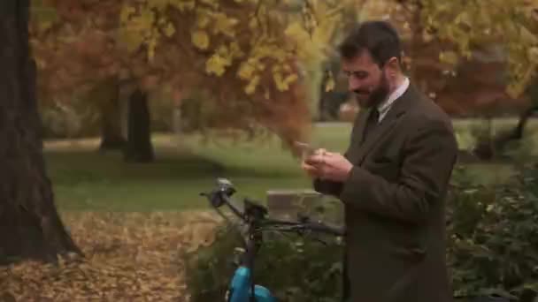 Красивый Молодой Человек Электрическим Велосипедом Помощью Мобильного Телефона Осеннем Парке — стоковое видео