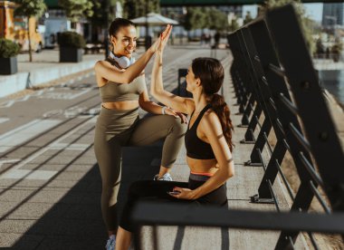 Spor kıyafetleri içinde nehir kenarında egzersiz yapan güzel genç kadınlar.