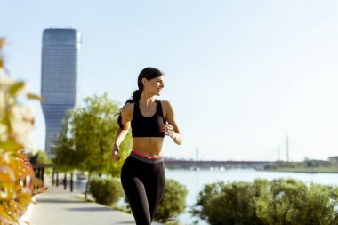 Güzel genç bayan nehir kenarında koşuya çıkıyor.