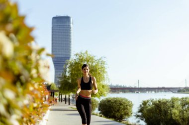 Güzel genç bayan nehir kenarında koşuya çıkıyor.