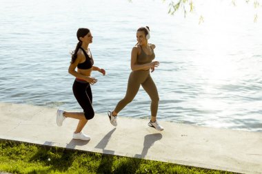 Güzel genç bayan nehir kenarında koşuya çıkıyor.