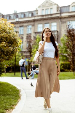 Sokakta yürürken cep telefonu kullanan güzel bir genç kadın.